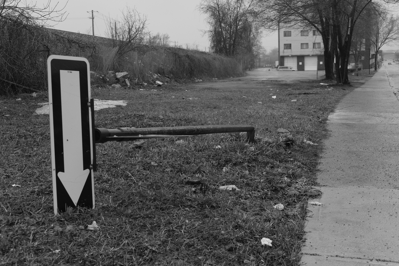 A one-way sign broken, fallen on the side
in a gray cityscape