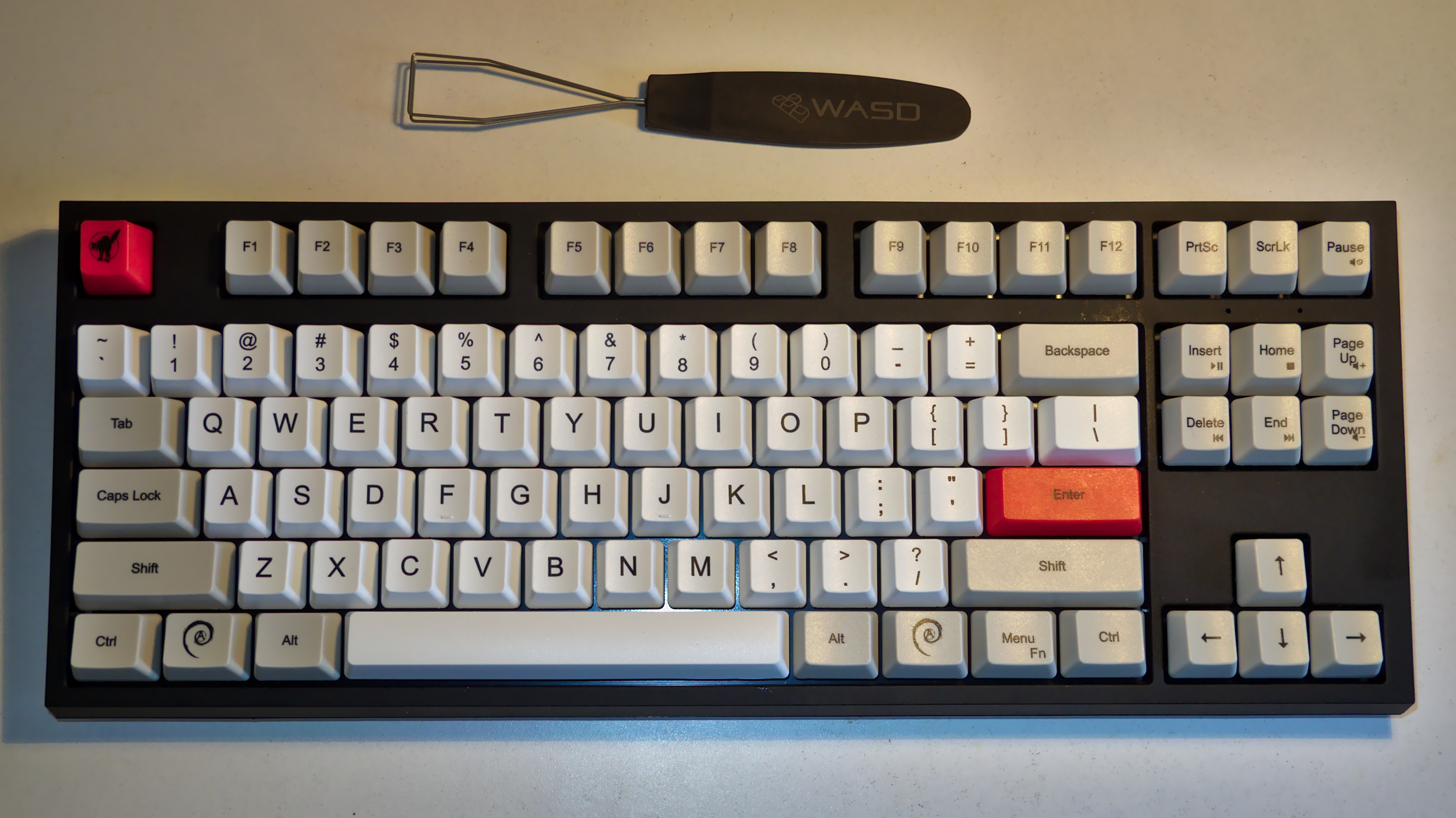 A photo of the keyboard which
has mostly white keys, except control keys in grey, enter and escape
in red. Key labels are in the middle of keys which is unusual.